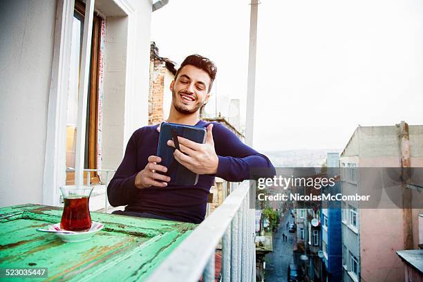 happy turkish man using digital tablet on his balcony - higher return stock pictures, royalty-free photos & images