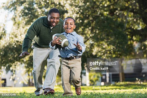 african american father and son playing football - american football action stock pictures, royalty-free photos & images