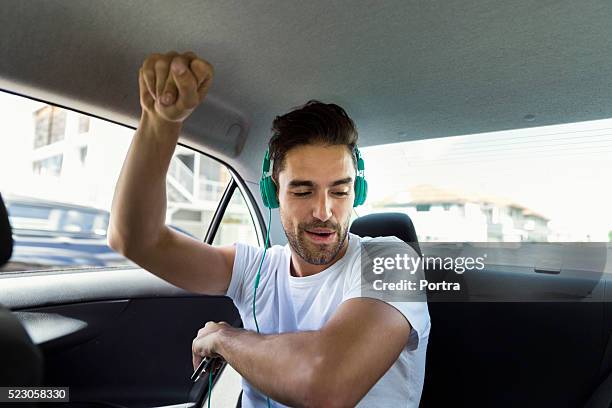 happy man dancing while listening to music in car - sitting on top of car stock pictures, royalty-free photos & images