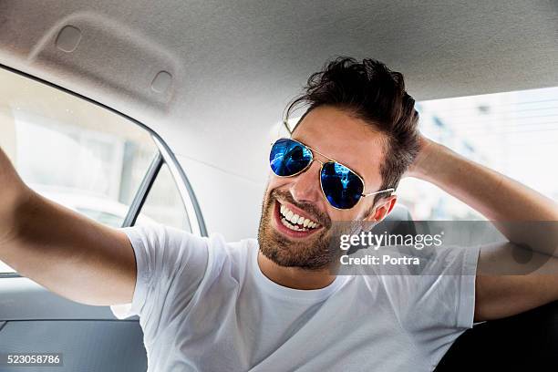 happy young man wearing sunglasses in car - man sunglasses stock pictures, royalty-free photos & images