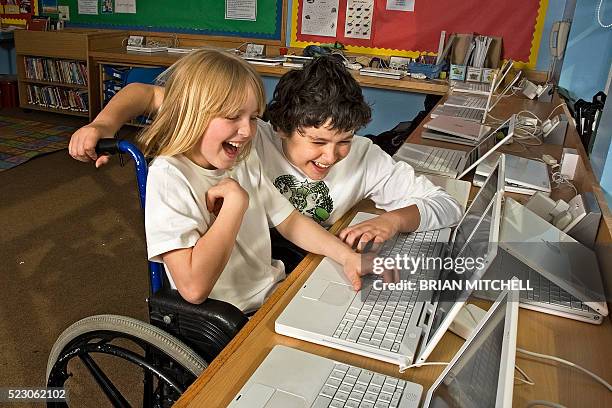 disabled boy in wheelchair with friend using laptop computer - ally mitchell stock pictures, royalty-free photos & images