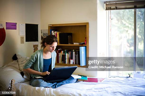 young college student in her dorm room working on the computer - residencia estudiantil fotografías e imágenes de stock