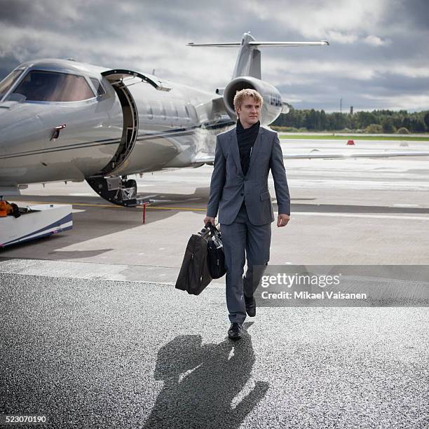 businessman walking across the tarmac - avión privado fotografías e imágenes de stock