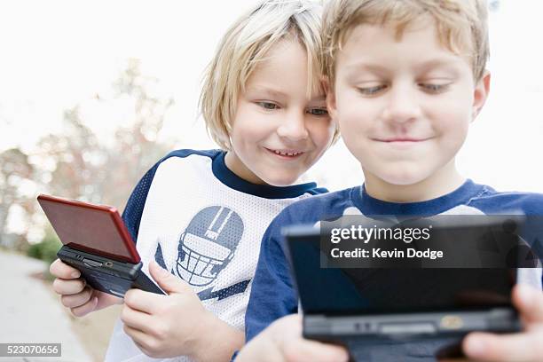 brothers playing handheld video games - handheld video game stock pictures, royalty-free photos & images