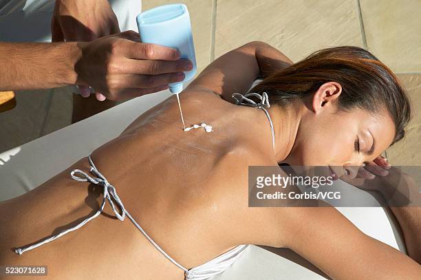 man putting suntan lotion on young woman - putting lotion stock pictures, royalty-free photos & images