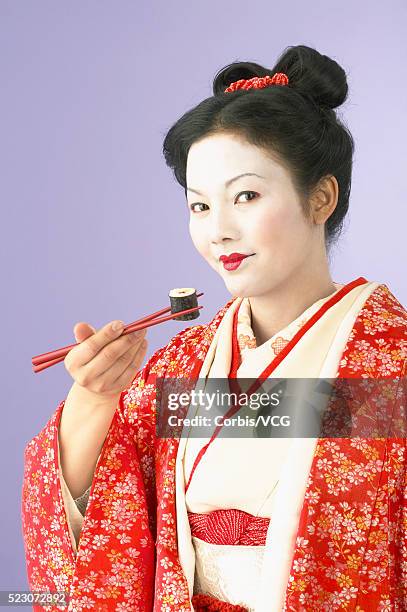 geisha holding sushi with chopsticks - geisha eating stockfoto's en -beelden