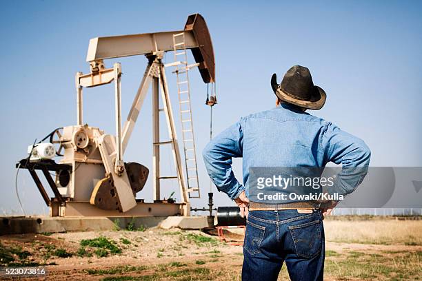 texas rancher looking at oil pumpjack - oil field fotografías e imágenes de stock
