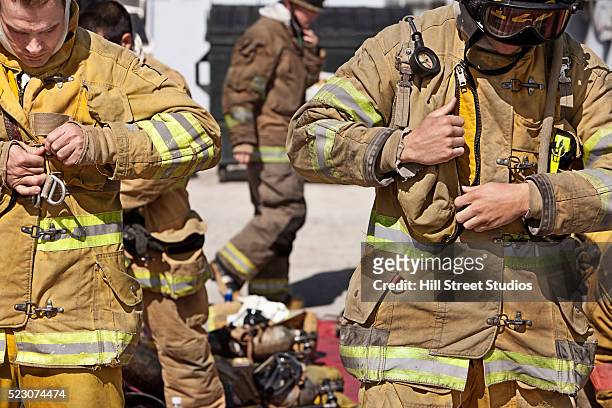 firefighters putting on firefighting suits - firefighter getting dressed stock pictures, royalty-free photos & images