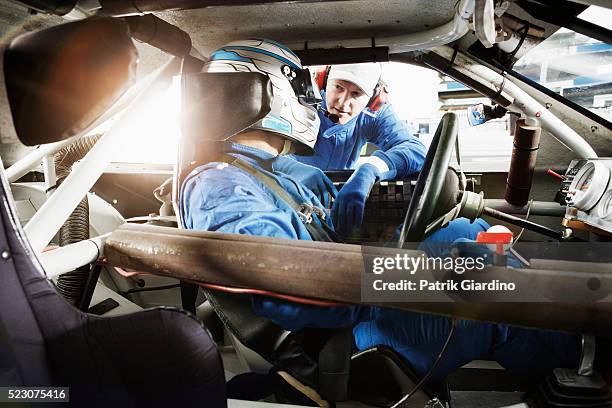 driver sitting in racecar and talking with coach - racing suit stock pictures, royalty-free photos & images