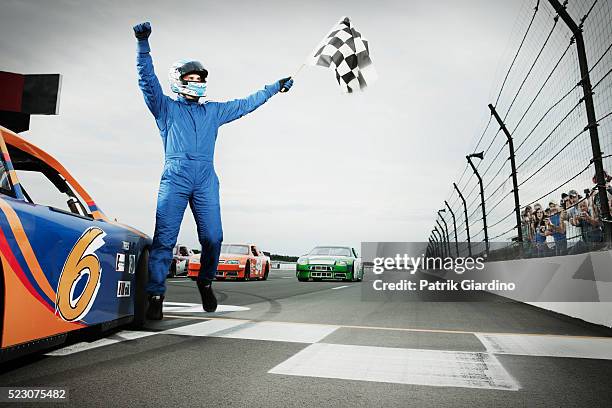 racecar driver jumping with checkered flag on sports track - piloto de coches de carrera fotografías e imágenes de stock