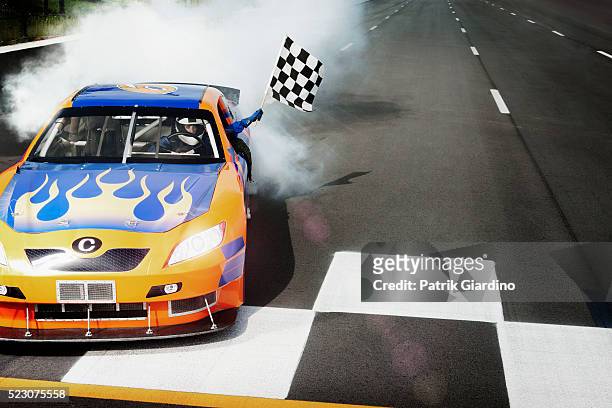 driver sitting in racecar and showing checkered flag - course de stock cars stockfoto's en -beelden
