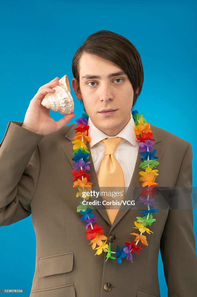 Young Businessman Wearing Lei and Listening to Shell
