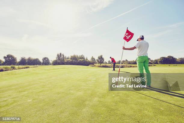 mid-adult men playing golf at sunset - golf clubhouse stockfoto's en -beelden