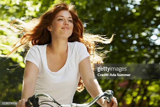 young woman riding bicycle, smiling - woman bicycle stock pictures, royalty-free photos & images