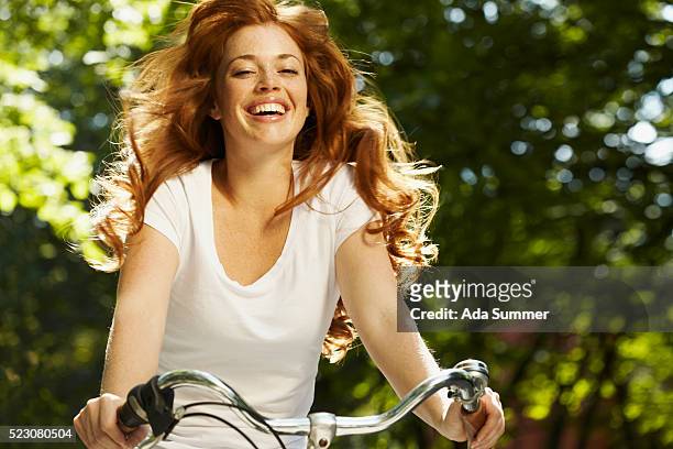 young woman riding bicycle, smiling - wavy hair stock pictures, royalty-free photos & images