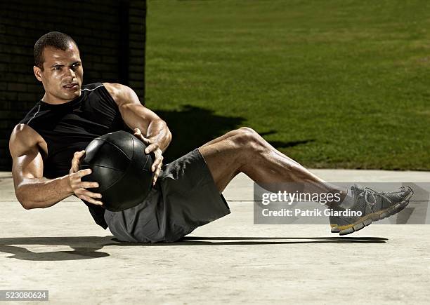 young man doing sit-ups with medicine ball - medicine ball stock pictures, royalty-free photos & images