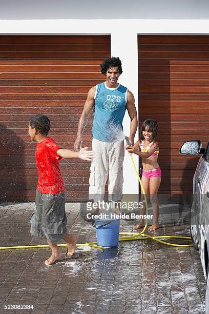 family having water fight in driveway - two kids playing with hose stock pictures, royalty-free photos & images