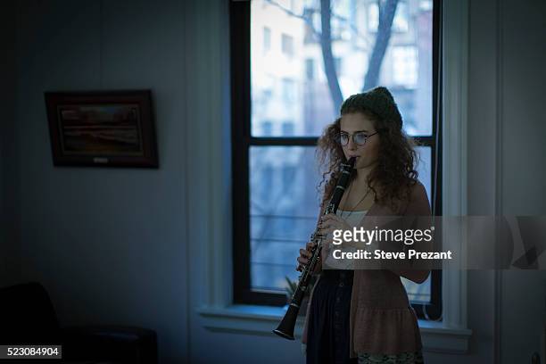 young woman playing clarinete at home - clarinete stockfoto's en -beelden