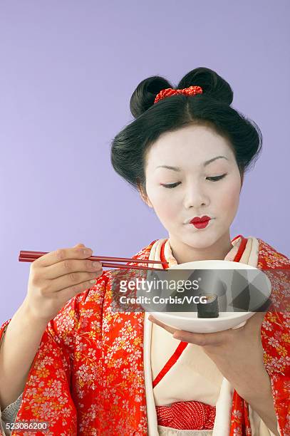 geisha holding sushi and chopsticks - geisha eating stockfoto's en -beelden