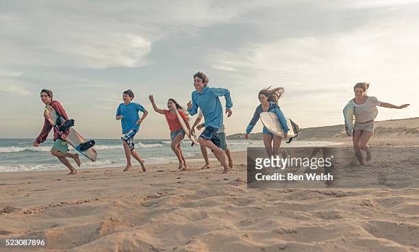 group of teenagers (13-17) with surfboards on beach - young teen girl beach stock pictures, royalty-free photos & images