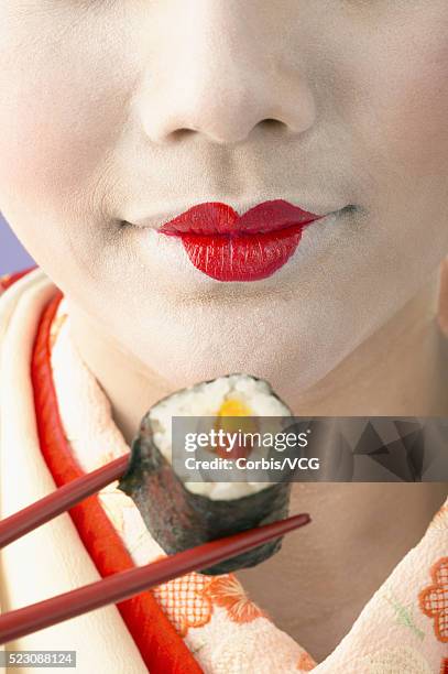 geisha holding sushi with chopsticks - geisha eating stockfoto's en -beelden