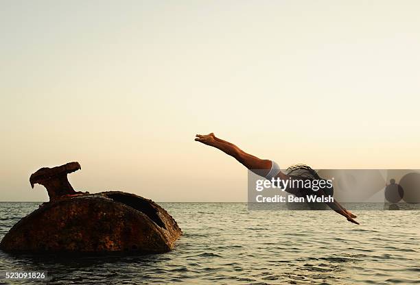 woman diving off a rusty tank into the water - vintage woman diving fotografías e imágenes de stock