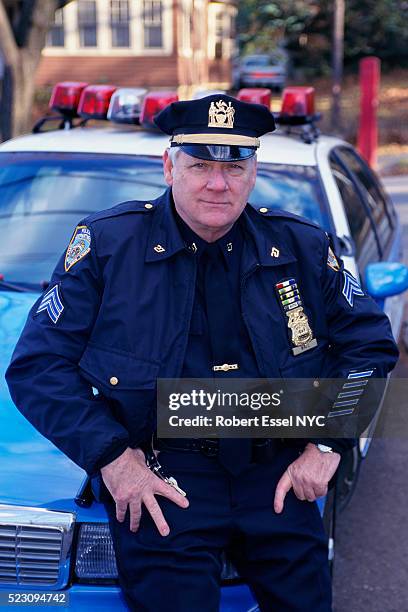 policeman posing on police car - uniforme della polizia foto e immagini stock