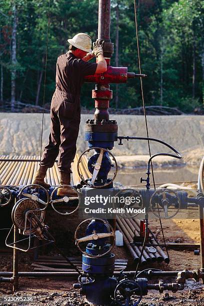 petroleum worker laboring on oil well pump - oil well stock pictures, royalty-free photos & images