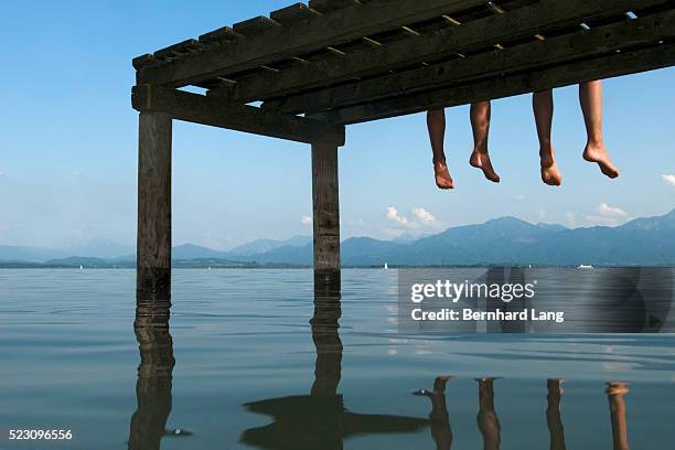 legs dangling off a jetty - lake chiemsee stock-fotos und bilder