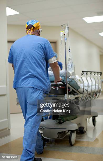 doctor pushing patient on stretcher in hospital corridor - stretcher photos et images de collection