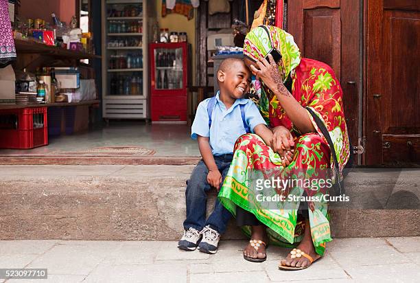 woman with son (7-9) on phone in east african market - east africa stock pictures, royalty-free photos & images
