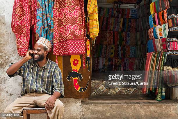 small business owner on phone in east african market - tanzania - fotografias e filmes do acervo