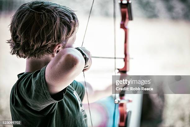 a young boy practices archery at camp in colorado - archery stock pictures, royalty-free photos & images