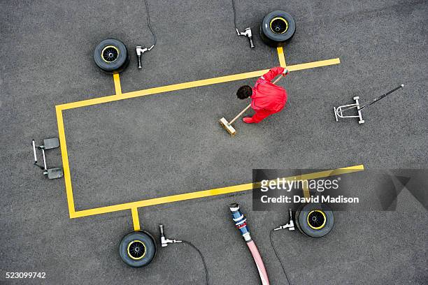 pit crew member sweeping pit box - pit stop stock pictures, royalty-free photos & images