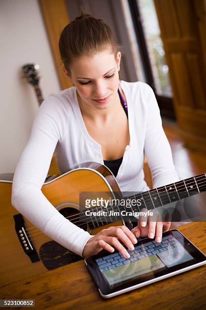 young woman playing guitar and using digital tablet - jim craigmyle guitar stock pictures, royalty-free photos & images