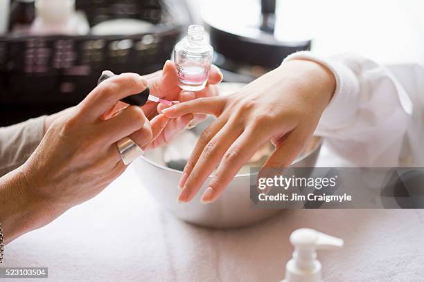 manicurist applying nail polish - manicure foto e immagini stock