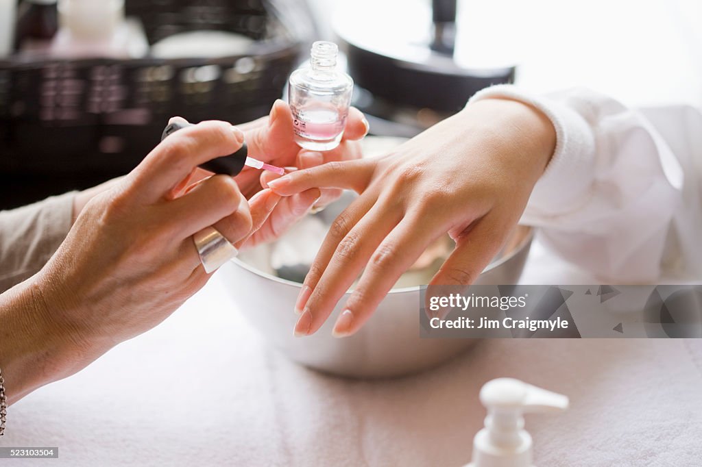 Manicurist applying nail polish