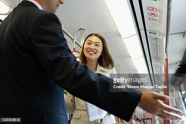 businessman giving away his seat on subway - seriös stock-fotos und bilder
