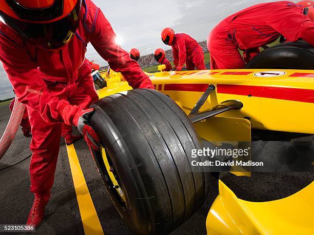 pit crew member changing tire on racecar - pit stop stock pictures, royalty-free photos & images