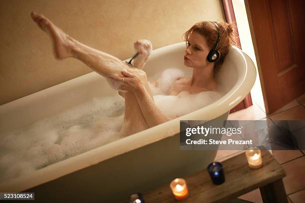 woman shaving legs in bathtub - shaving foto e immagini stock