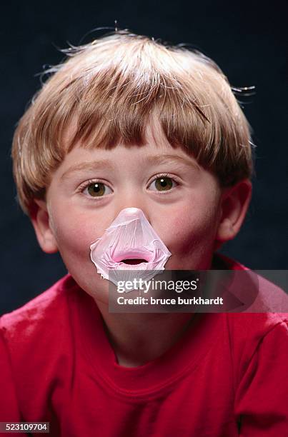 boy with popped gum bubble on his mouth - masticar fotografías e imágenes de stock