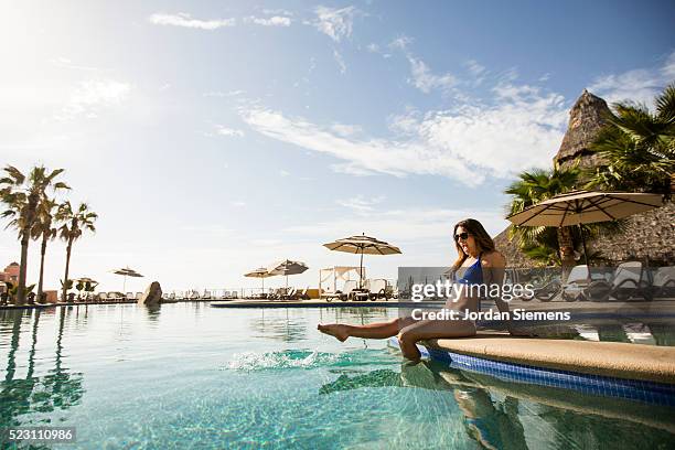 woman sitting on edge of pool, cabo san lucas, mexico - cabo san lucas stock-fotos und bilder