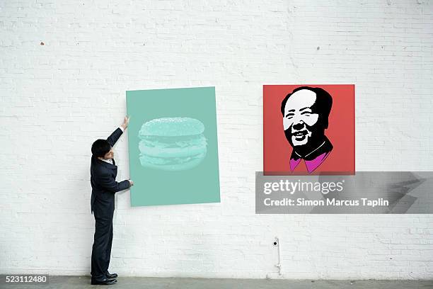 man hanging a painting - kunsthändler stock-fotos und bilder