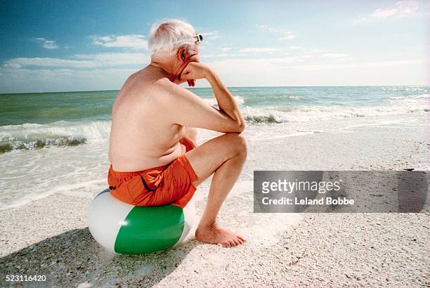elderly man sitting on beach ball - sulking stock-fotos und bilder