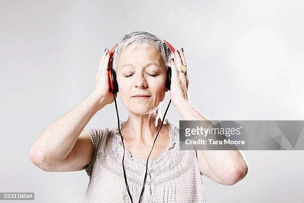 older lady listening to music on headphones - music enjoyment stock pictures, royalty-free photos & images