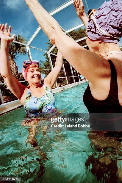 senior women exercising in swimming pool - aquarobics stock pictures, royalty-free photos & images