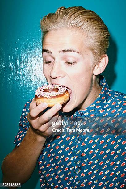 young man eating donuts - donut man stock pictures, royalty-free photos & images