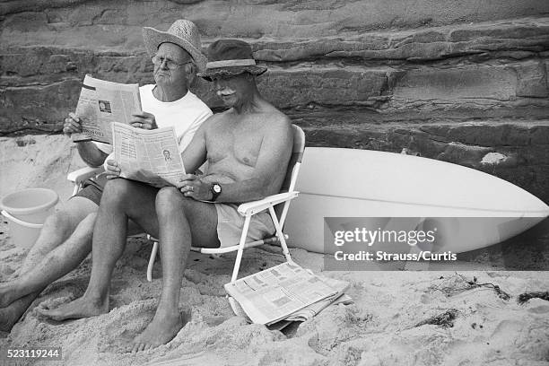 elderly men reading newspapers on beach - vintage surf stock pictures, royalty-free photos & images