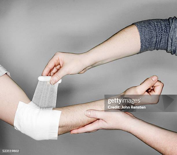 woman bandaging a man's elbow - wunde stock-fotos und bilder