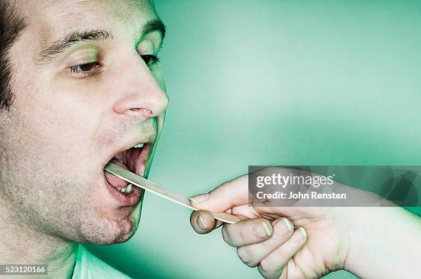 examining a man's throat - tongue depressor stock pictures, royalty-free photos & images
